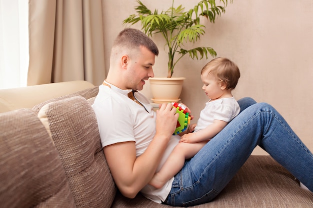 El padre juega con la pequeña hija, pasa tiempo juntos y se divierte en el sofá