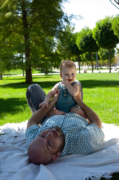 Foto padre juega con su hijo pequeño en el parque en el césped aire fresco de verano paternidad familiar