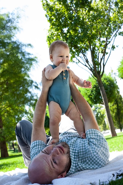 Foto padre juega con su hijo pequeño en el parque en el césped aire fresco de verano paternidad familiar