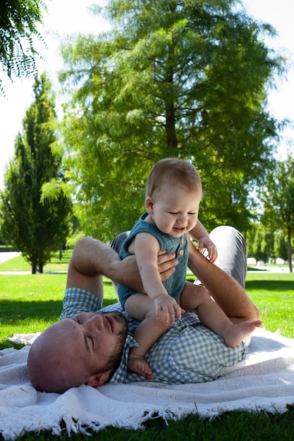 Foto padre juega con su hijo pequeño en el parque en el césped aire fresco de verano paternidad familiar