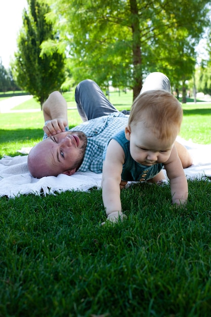 Foto padre juega con su hijo pequeño en el parque en el césped aire fresco de verano paternidad familiar