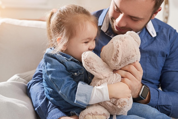 Padre jugando con hija con osito de peluche