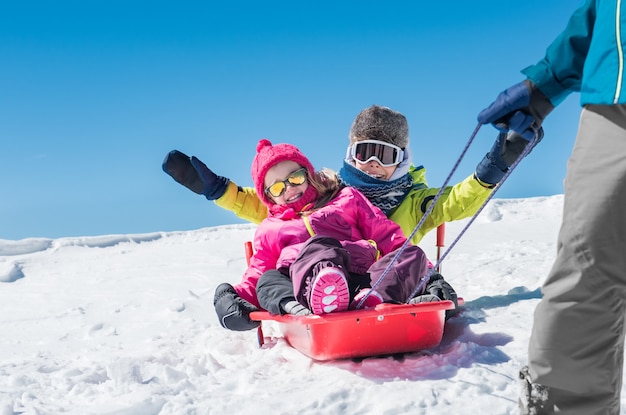 Padre jugando con niños en la nieve