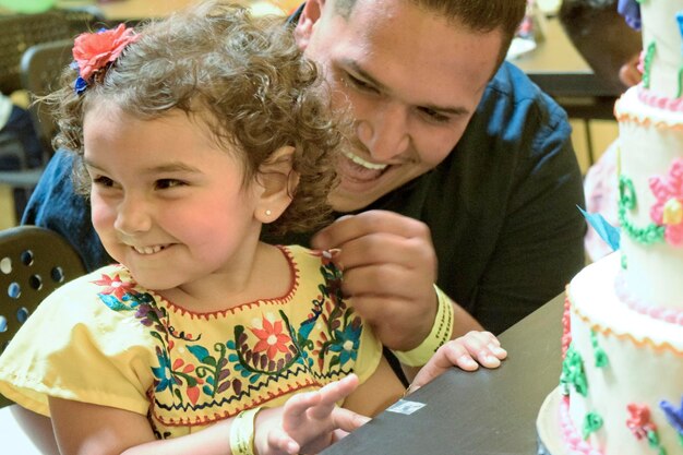 Padre jugando con su hija junto al pastel en la mesa