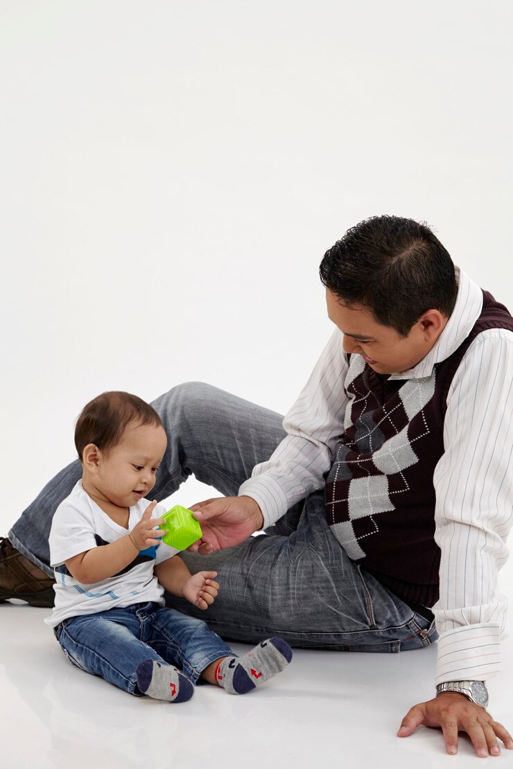 Foto padre jugando con su hijo sentado contra un fondo blanco