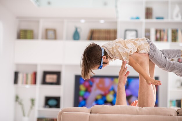 Padre jugando con su pequeño hijo en el sofá en casa