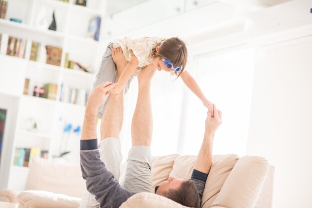 Padre jugando con su pequeño hijo en el sofá en casa