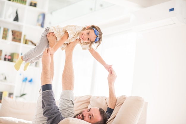 Padre jugando con su pequeño hijo en el sofá en casa