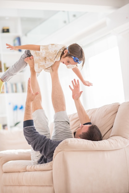 Padre jugando con su pequeño hijo en el sofá en casa