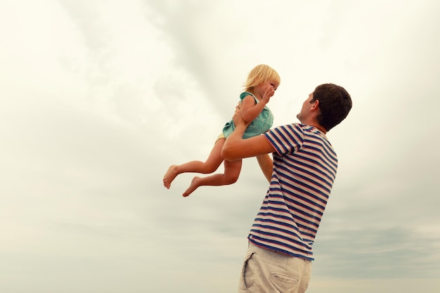 Padre lanza hacia arriba niño riendo Unas vacaciones familiares en la playa Copiar espacio