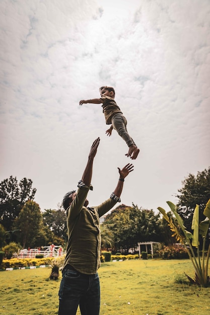Foto padre lanzando a su hijo en el aire mientras está de pie en el parque