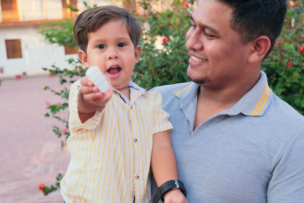 Padre latino sosteniendo a su hijo mientras come dulces