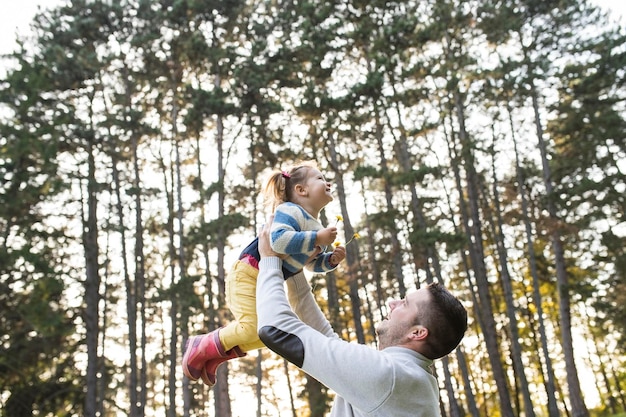 Padre levantando a su hija en el bosque