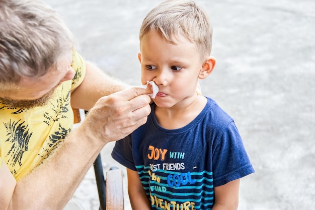 El padre limpia la cara del niño en edad preescolar de las sobras de helado