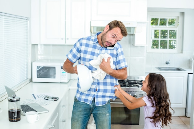 Padre limpiando el contenedor mientras su hija tira de él