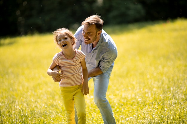 Padre con linda hijita divirtiéndose en la hierba en el parque