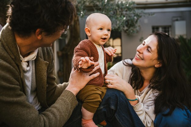 Foto padre y madre alegres sosteniendo a su hijo al aire libre