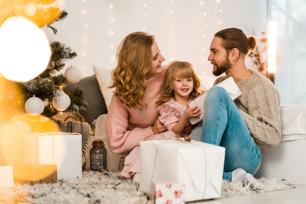 Padre y madre dan a su hija regalos de navidad.