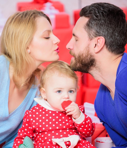 Padre, madre e hija. Comprar en linea. Día de San Valentín. Cajas rojas. Familia feliz con caja actual. Amor y confianza en la familia. Hombre barbudo y mujer con niña. Totalmente enamorado.