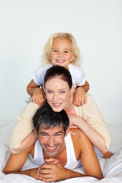 Padre, madre e hija jugando en la cama