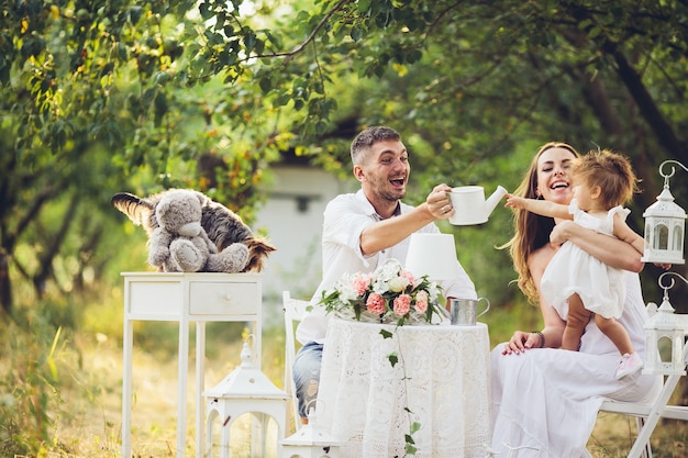 Padre, madre e hija juntos en el picnic en el jardín