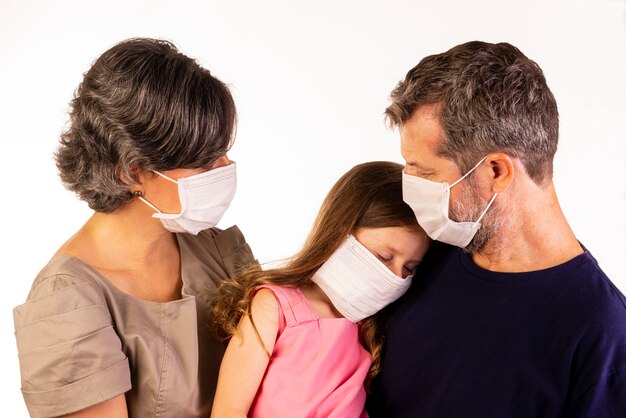 Padre, madre e hija con máscaras protectoras sobre fondo blanco.