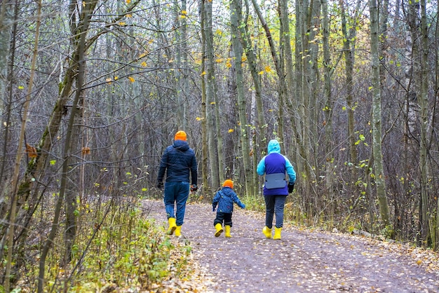 Padre, madre e hijo se alejan por el camino del otoño.