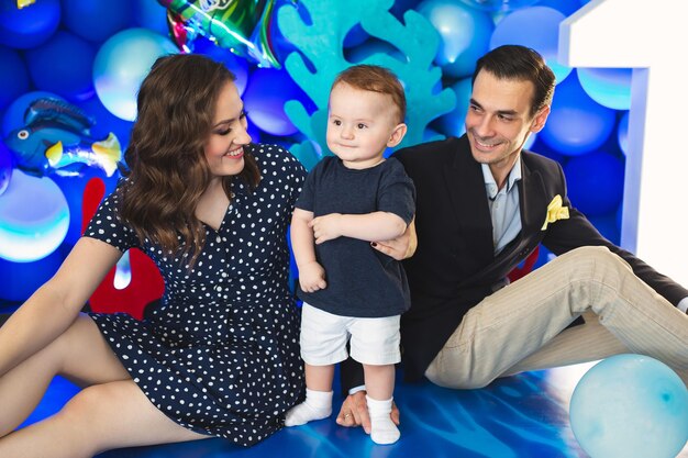 Padre, madre e hijo en el fondo de la decoración azul en estilo marinero en la fiesta.