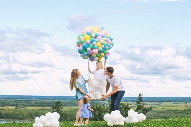 Padre de madre de familia y dos hijas con un dirigible de globo en el fondo de cielo azul