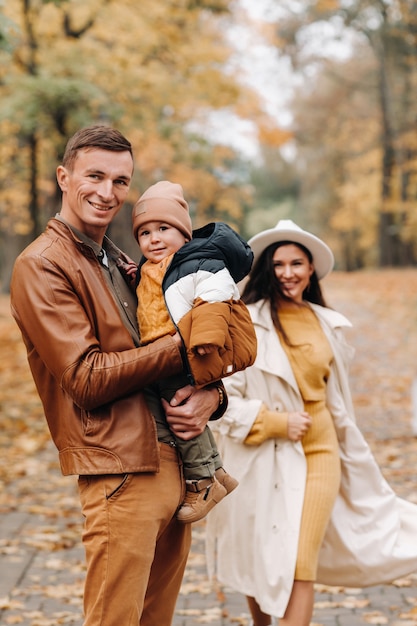 Padre y madre con hijo caminando en el parque de otoño