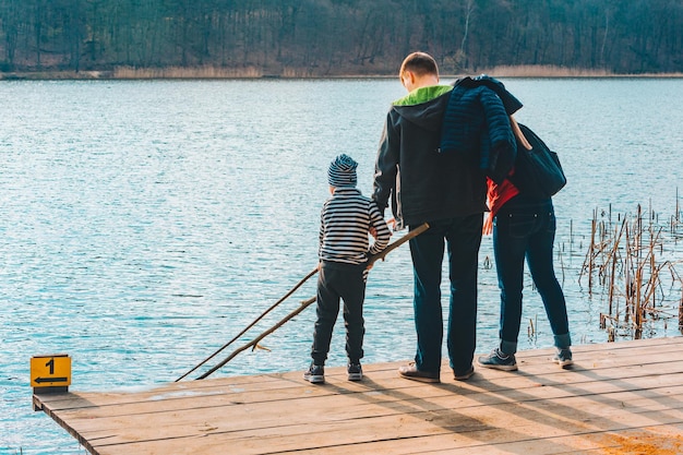 Padre y madre con niño jugando con un banco cerca del agua