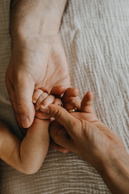 Padre y madre sosteniendo la mano del pequeño bebé recién nacido