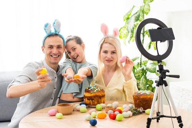 Padre, madre y su hijo disfrutan pintando huevos de Pascua. Compre en línea para la decoración de felices pascuas. Huevos de Pascua - surtido de huevos de colores.