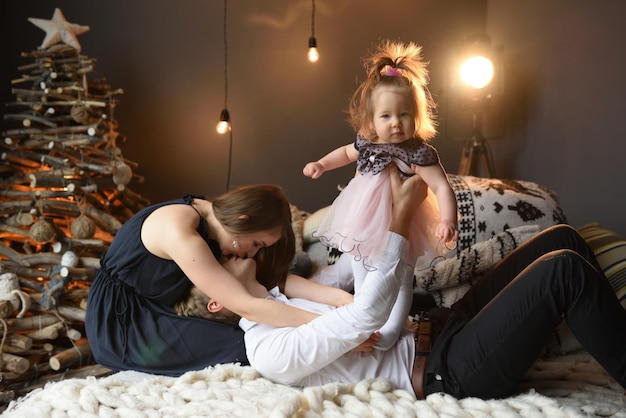 Padre mamá y su pequeña hija de un año se divierten juntos antes de navidad