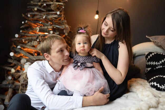 Padre mamá y su pequeña hija de un año se divierten juntos antes de navidad