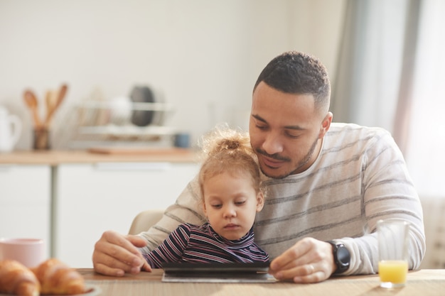 Padre moderno con tableta digital con niña linda