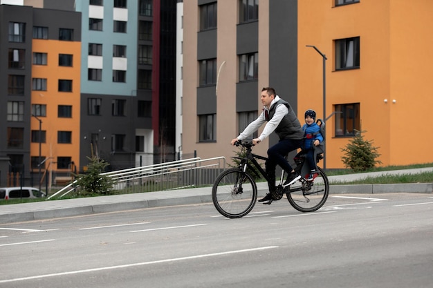 Padre montando en bicicleta con su hijo en el asiento de la bicicleta