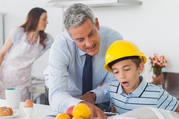 Foto padre mostrando a hijo sus planos mientras está usando casco