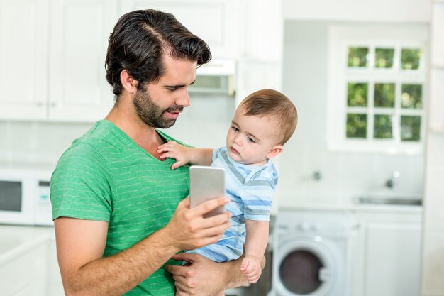 Padre mostrando teléfono móvil a lindo bebé