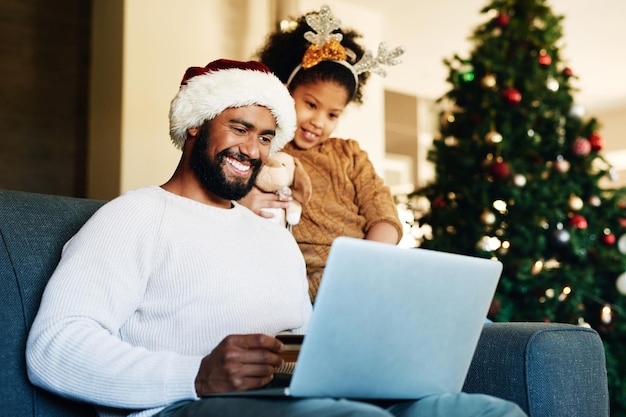 Padre niña y computadora portátil con tarjeta de crédito de comercio electrónico navideño o compras en línea con una sonrisa en casa Papá hija y compras con computadora para regalo o regalo en la sala de estar en casa familiar