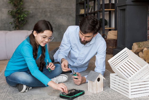 Padre y niña construyendo una casa para pájaros