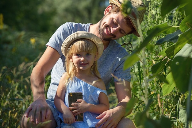 Padre y niña usando un teléfono móvil en el campo.