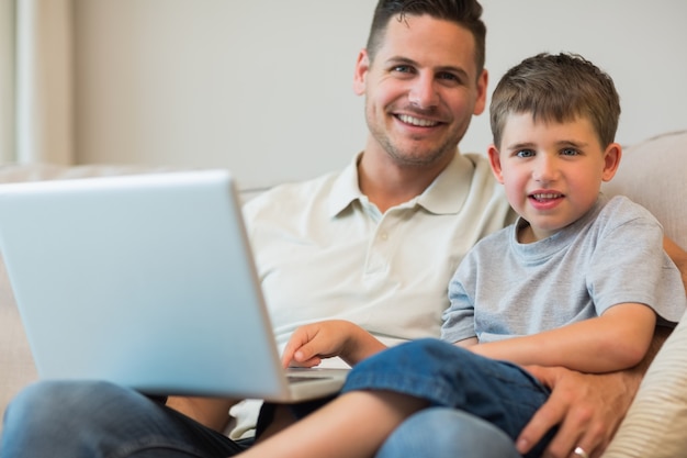 Foto padre y niño con la computadora portátil en el sofá
