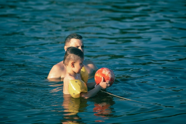 Foto padre con niño divirtiéndose en el agua nadando juntos