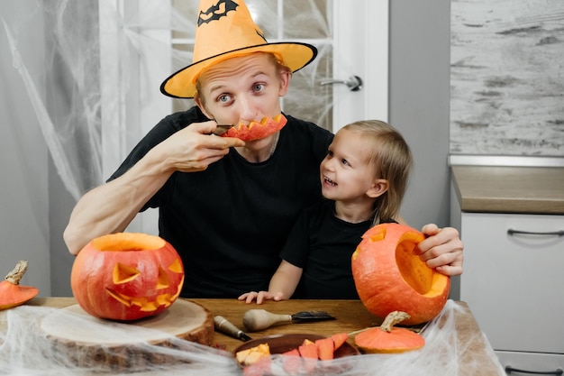 Padre con niño está tallando calabaza para halloween