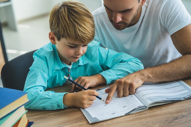 El padre y un niño haciendo los deberes en el escritorio.