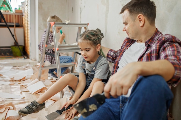 Padre con niño reparando habitación juntos y papel tapiz inmutable juntos