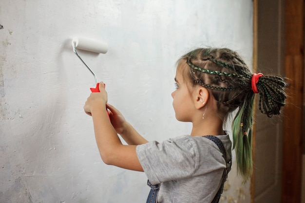 Padre con niño reparando habitación juntos y pintando la pared juntos