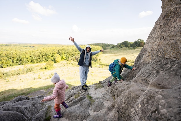 Padre con niños escalando piedra grande en la colina Pidkamin Ucrania