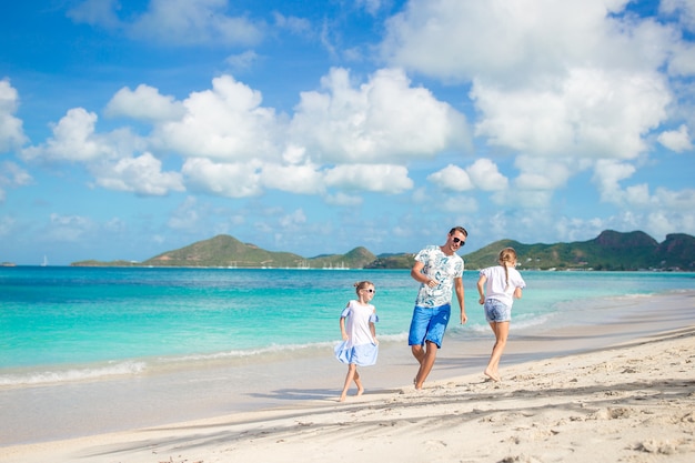 Padre y niños pequeños disfrutando de vacaciones de verano playa tropical. Familia jugando en la playa